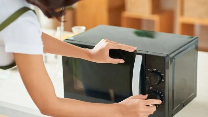 Woman setting time on the microwave