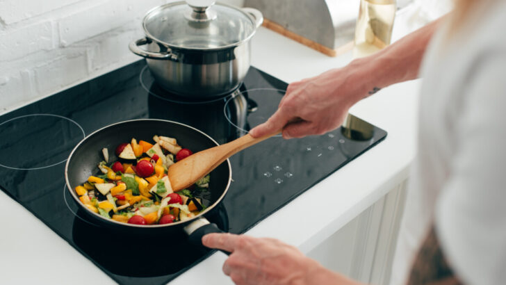 Man stir-fry vegetables in an electric stove
