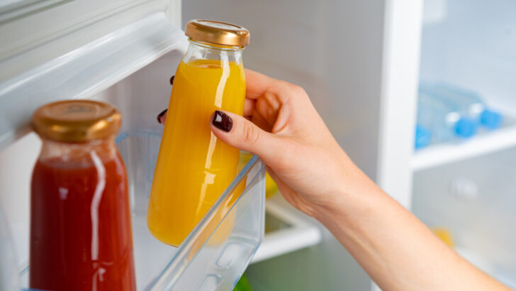 Female taking a bottled orange juice from a fridge 