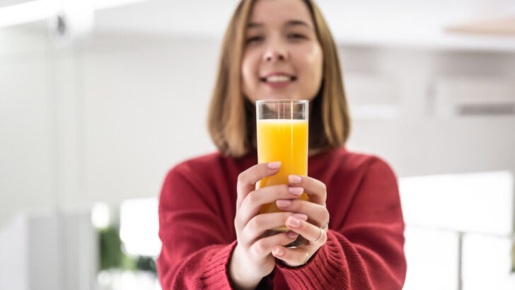 Glass of orange juice in the hands of a happy young woman