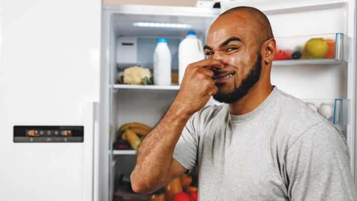 male pinching his nose for bad smell from rotten pork in the fridge