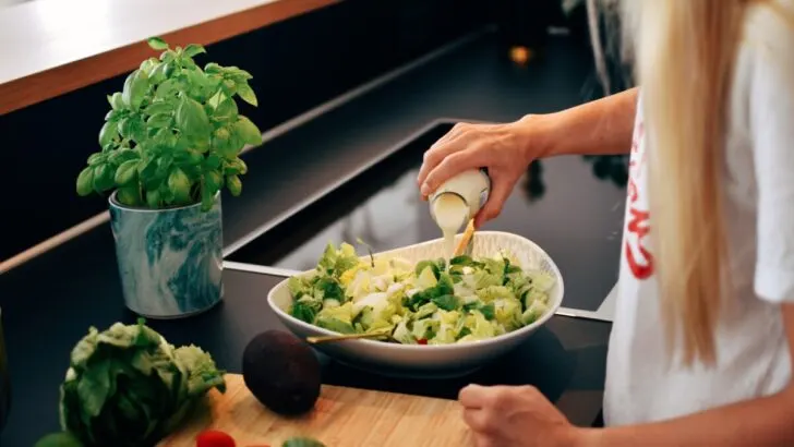 woman putting dressing to the salad