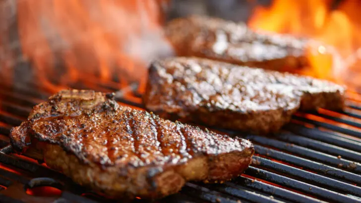 Grilling steaks on flaming grill