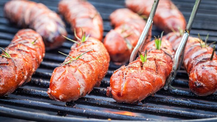 Tasty sausage on hot grill with spices and herbs
