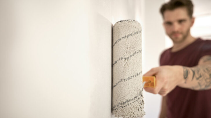 Man painting wall in new house with a paint roller